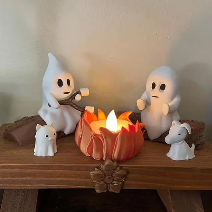 Ghost Bonfire Party Night Light and two dog figurines gathered around a lit candle on a wooden surface.