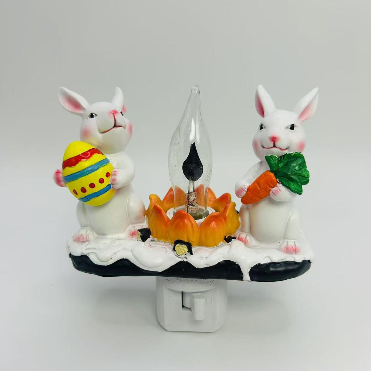 Decorative night light with rabbit figures holding Easter items on a white background
