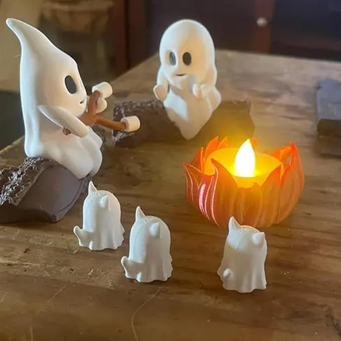 Set of small ghost figurines around a lit candle on a wooden surface