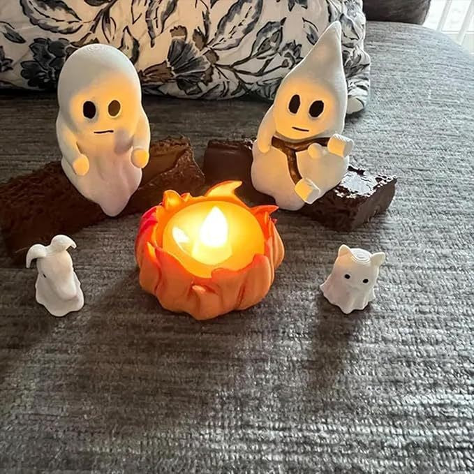 Set of Halloween-themed figurines around a small candle on a textured surface.